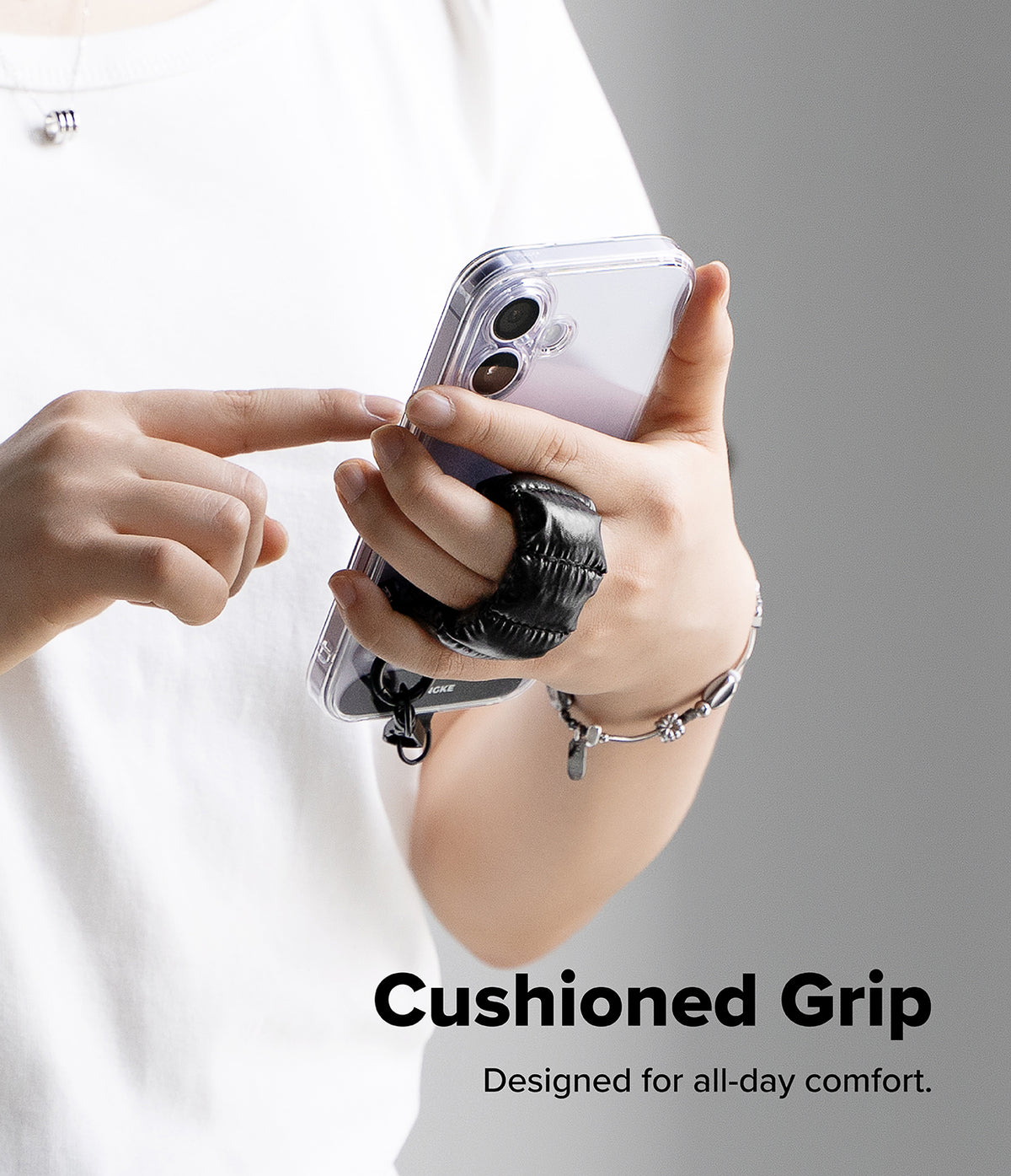 Holder Link Puffer | Finger - A person holding a phone with a black, quilted, cushioned finger strap for a secure grip.