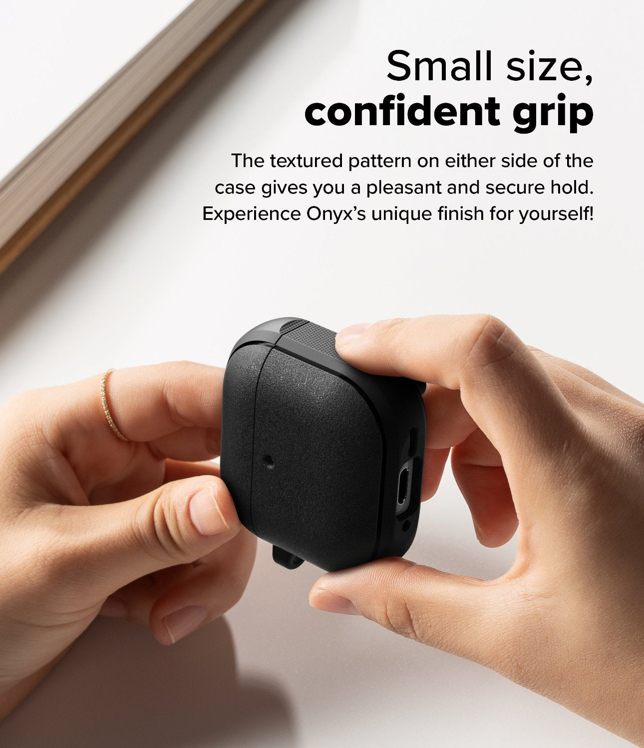 AirPods 4 Case | Onyx Magnetic - Hands holding a black textured AirPods 4 case with side grip patterns on a white surface.