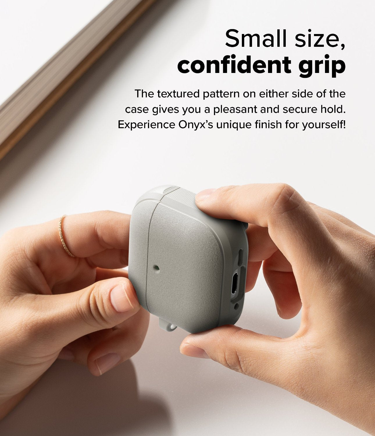 AirPods 4 Case | Onyx Magnetic - Hands holding a grey textured AirPods 4 case with side grip patterns on a white surface.