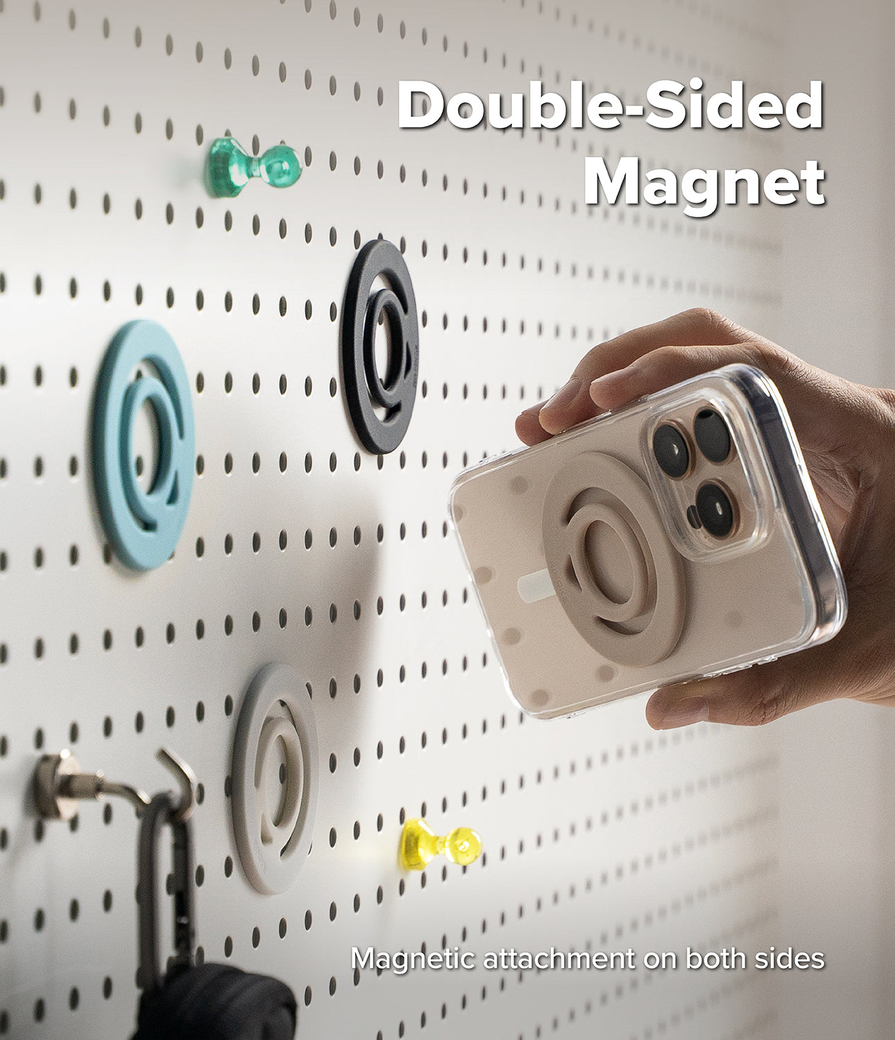 Dual Magnetic Silicone Ring - Hand holding a phone with a magnetic ring attached to a pegboard wall with other rings.