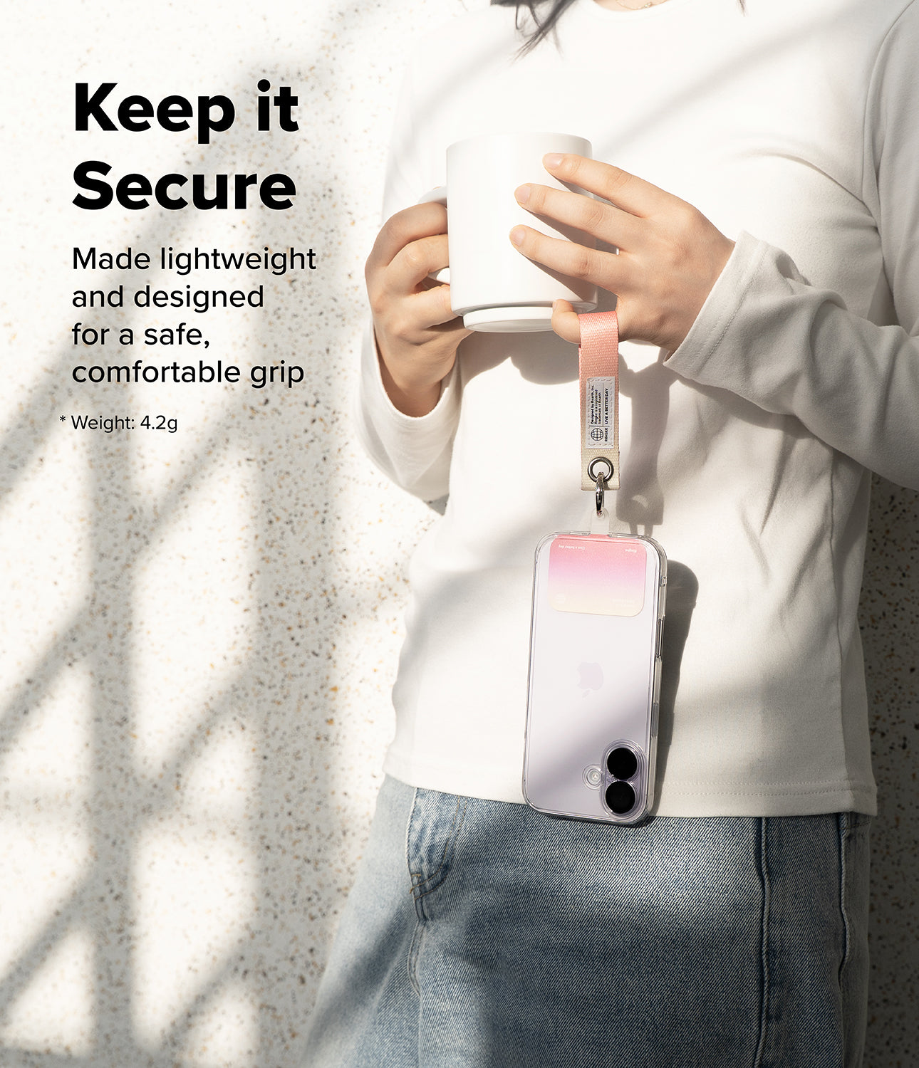 Holder Link Eyelet Keyring - A person holding a mug with a phone attached to a pink wrist strap hanging from their hand.