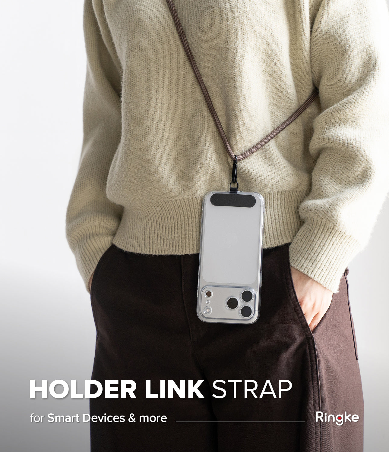 Holder Link Strap | Black - Person wearing a clear phone case on a black neck strap over a beige sweater and brown pants.