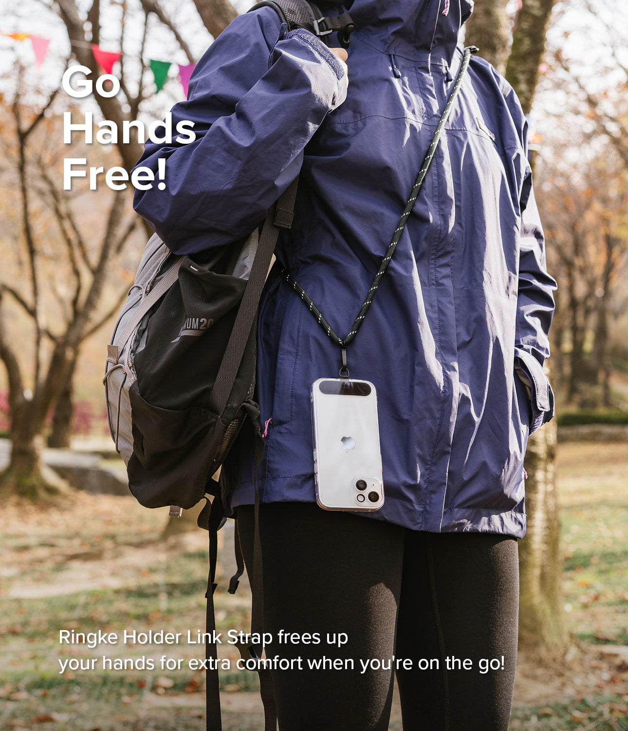 Holder Link Strap | Black - Person wearing a black phone lanyard strap over a blue jacket with a backpack in a park.