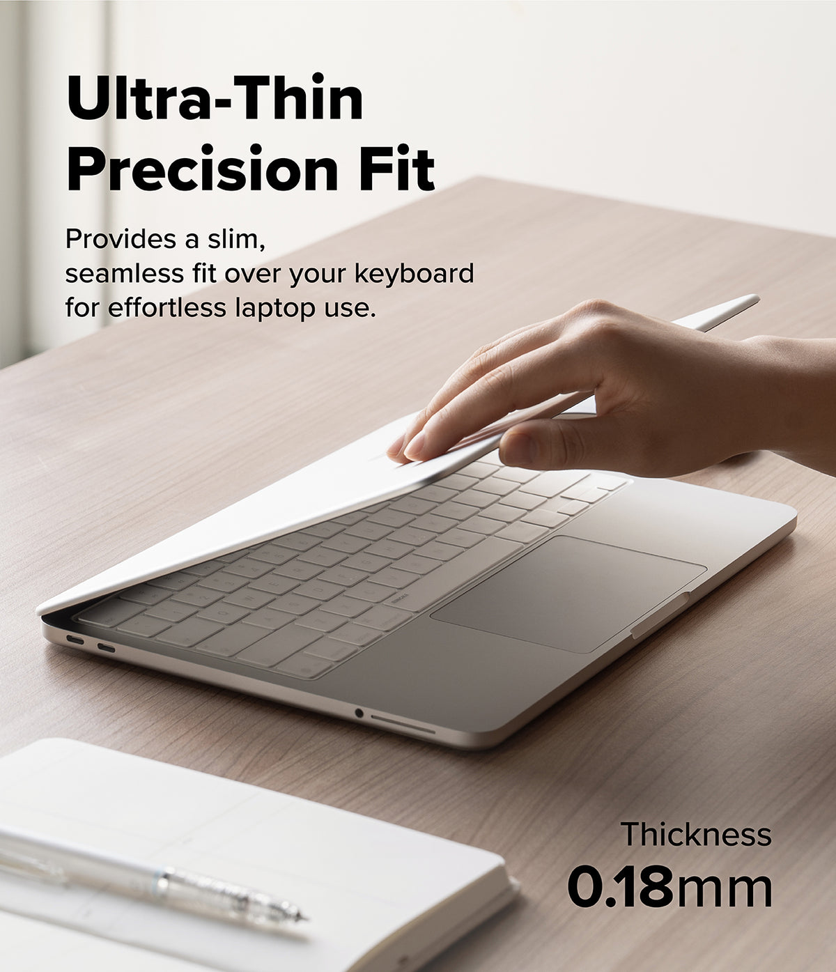 MacBook Neo | Keyskin - A hand is shown pressing down on a slim silver laptop skin or cover placed over a laptop keyboard on a wooden desk. Text reads 'Ultra-Thin Precision Fit' and 'Provides a slim, seamless fit over your keyboard for effortless laptop use.