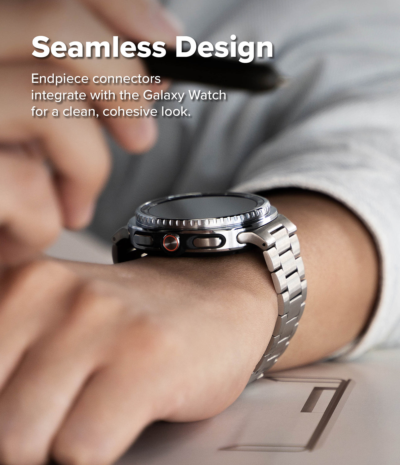 Galaxy Watch 9 / 8 | Metal One Air - Close-up of a smartwatch with a silver metal band worn on a person's wrist, with overlaid text reading 'Seamless Design' and smaller explanatory copy about endpiece connectors.
