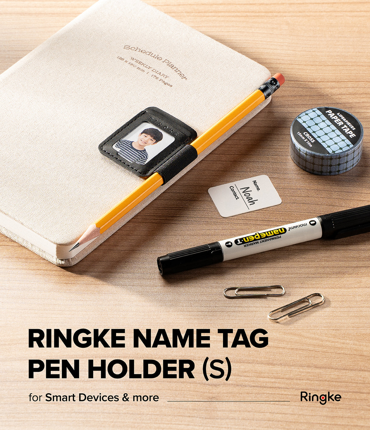 Pen Holder | Name Tag (2P) - A Ringke name tag pen holder set displayed on a light wood desk, featuring a black ring holder with a sample photo, a yellow pencil, a black marker, paper clips, washi tape, and a small card. Text at the bottom reads 'RINGKE NAME TAG PEN HOLDER (S)'.