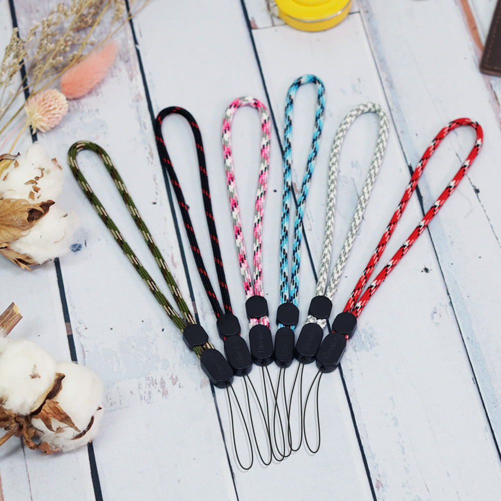 6 braided wrist straps in various colors are arranged in a row on a white wooden surface