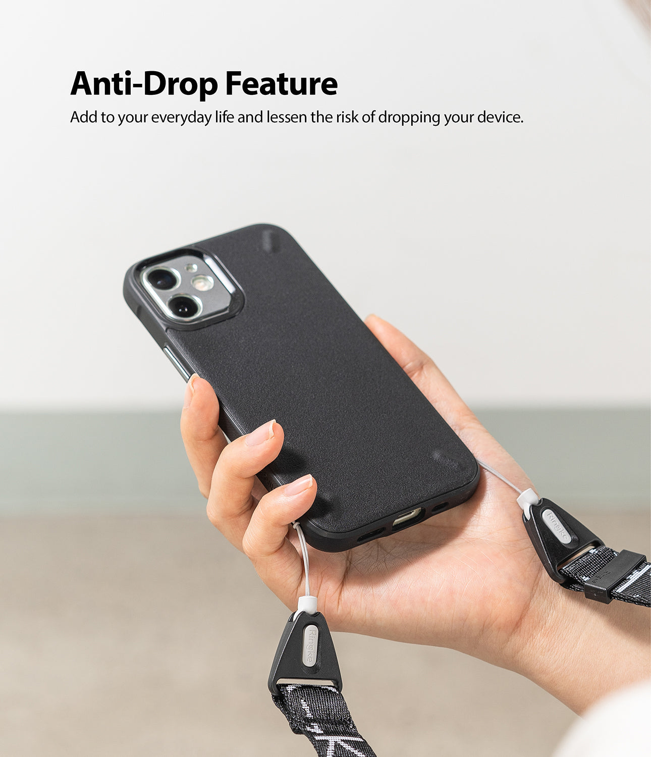 Shoulder Strap | Lettering - Hand holding a black phone case attached to a branded black shoulder strap with white lettering.
