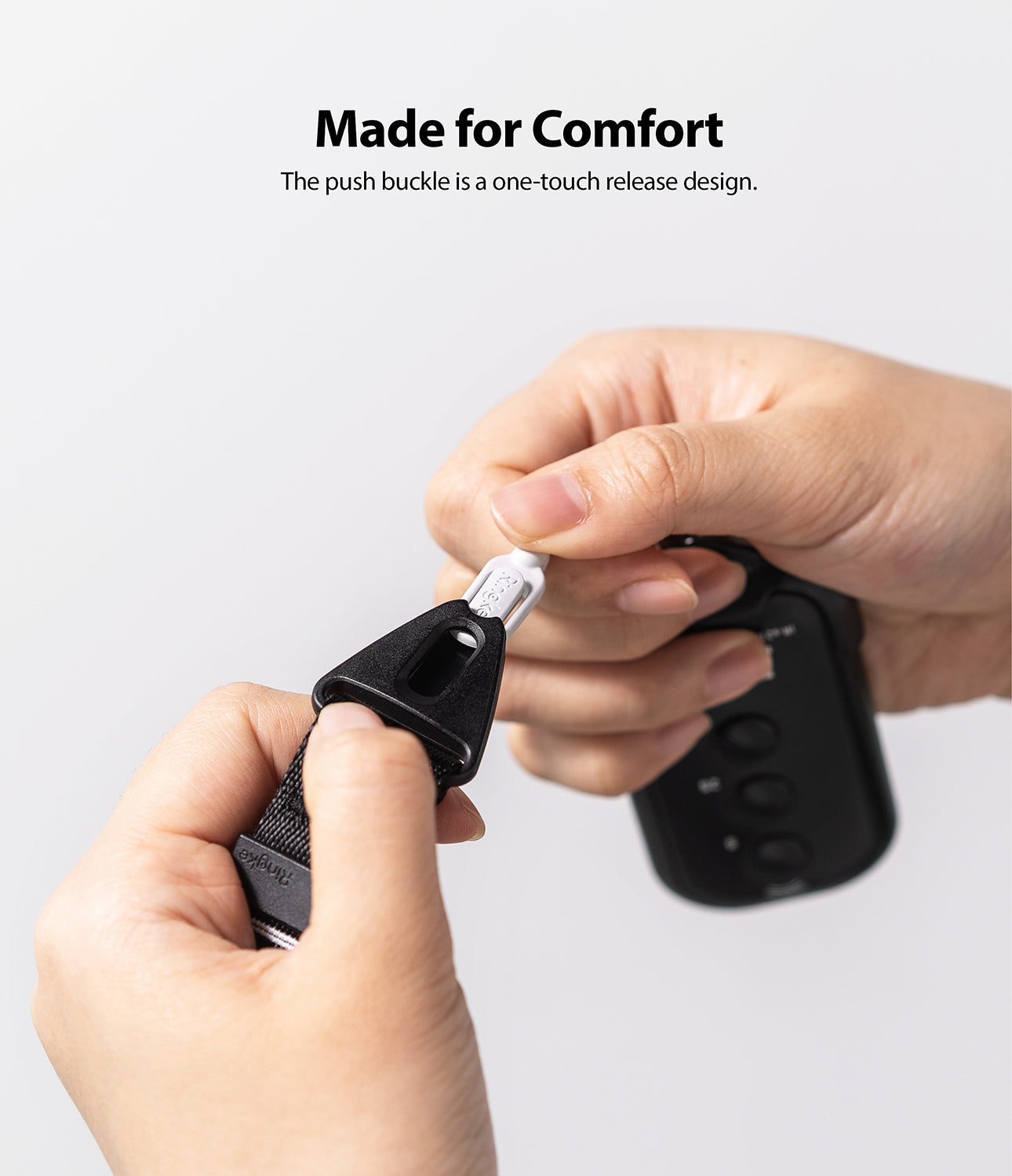Shoulder Strap | Lettering - Hands detaching a black push-buckle strap from a white connector on a black device.