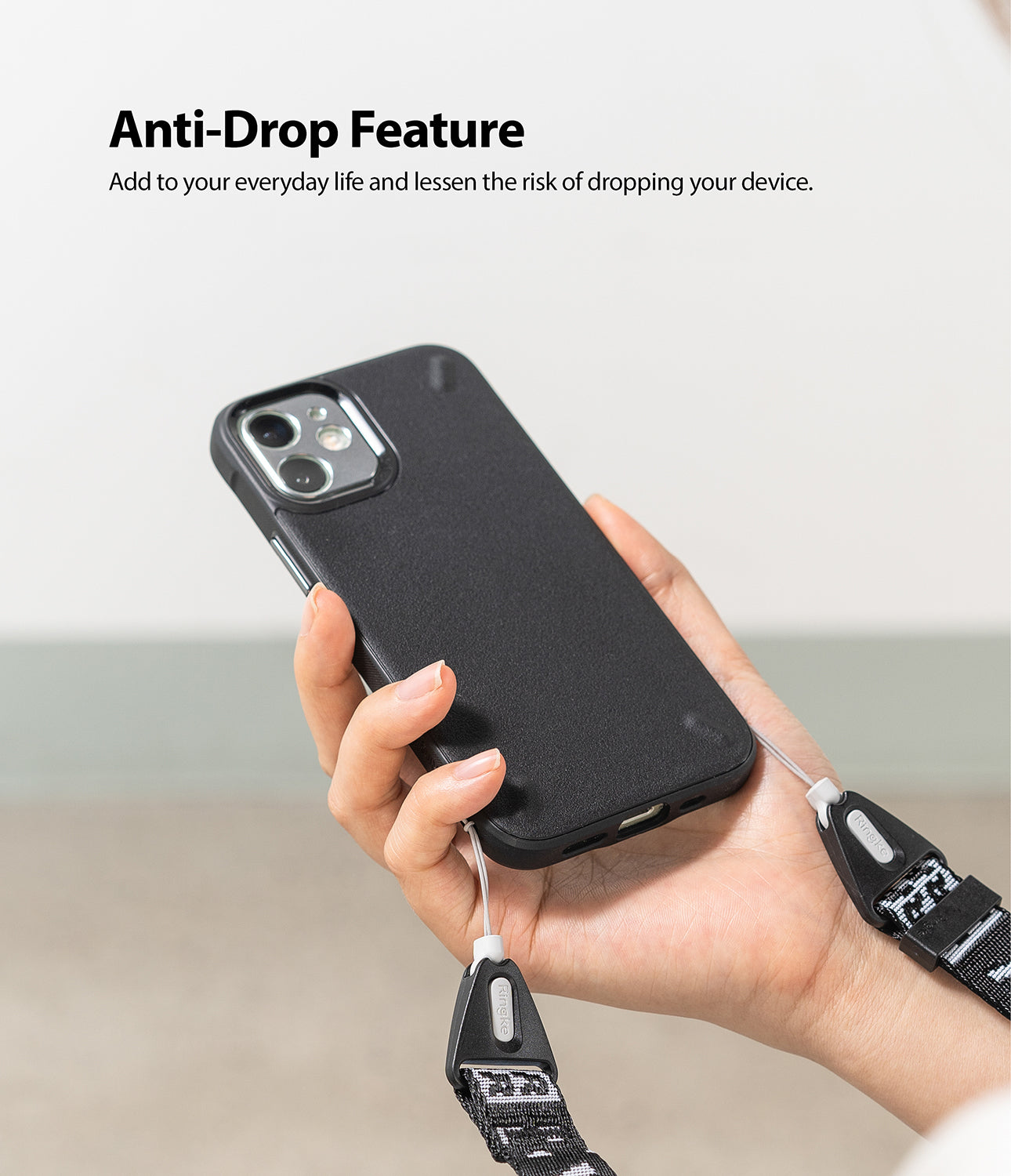 Shoulder Strap | Lettering - Hand holding a black phone case attached to a patterned Ringke shoulder strap for anti-drop safety.