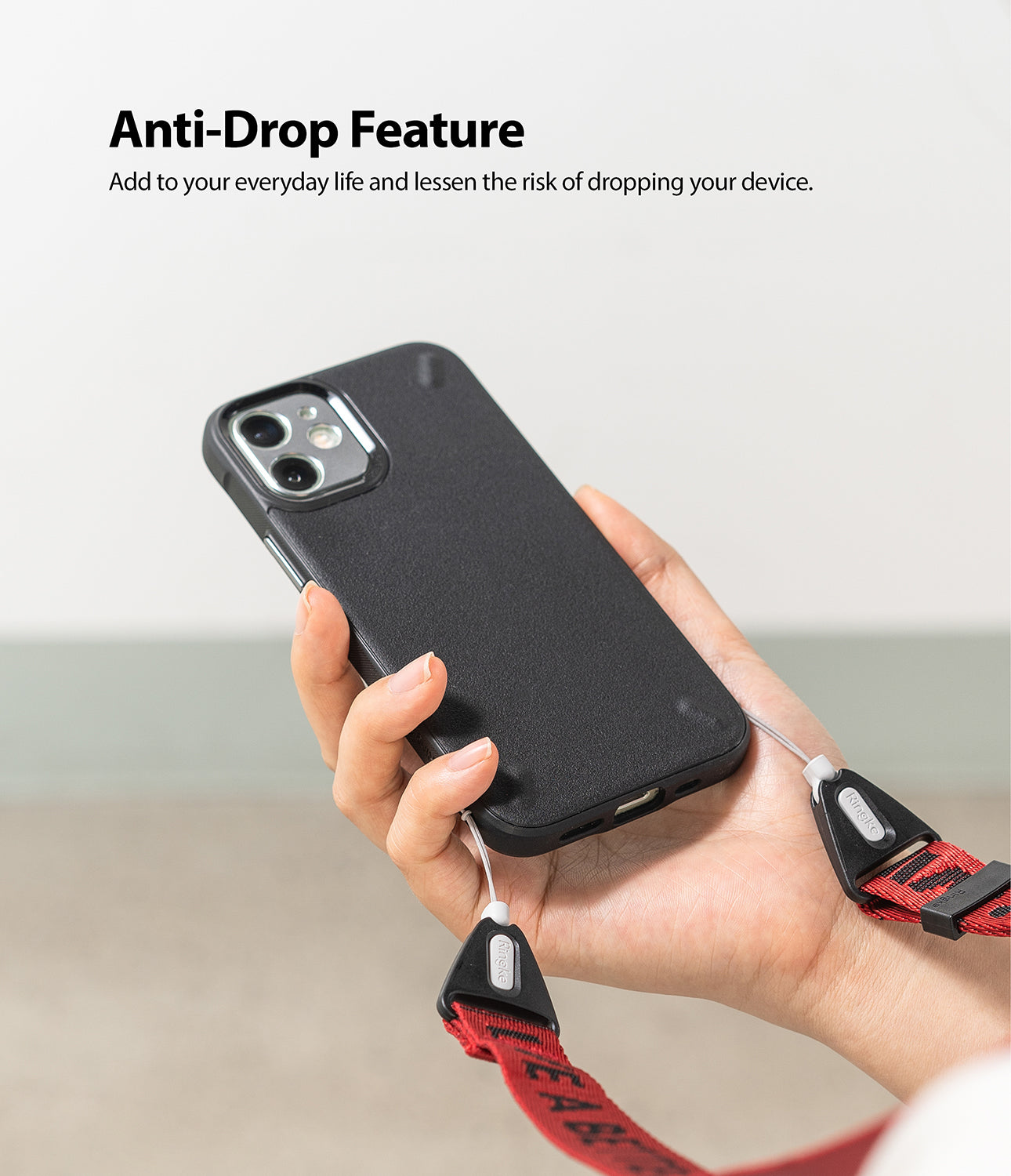 Shoulder Strap | Lettering - Hand holding a black phone case attached to a red Ringke shoulder strap with black lettering.