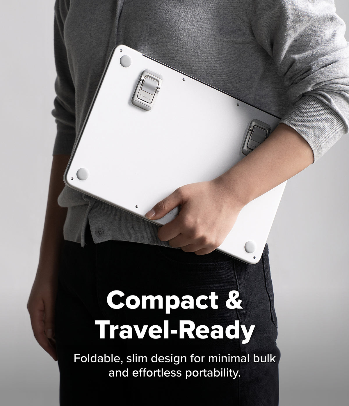 Step-Fit Mini Stand - A person in a gray sweater holds a compact white foldable travel case against their shoulder, with text reading 'Compact & Travel-Ready' and 'Foldable, slim design for minimal bulk and effortless portability.' on a light gray background.