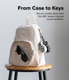 Holder Link Puffer | Finger - Cream backpack with puffer finger straps and sunglasses, displayed on a wooden stool.