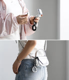 Holder Link Puffer | Finger - Person holding a silver handbag with a crystal strap against a plain background