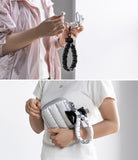 Holder Link Puffer | Hand - Person holding a silver handbag with a black strap, wearing a white shirt.