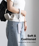 Holder Link Puffer | Hand - Person holding a black backpack with a silver puffer hand strap, wearing a white shirt and blue jeans on a gray background.