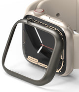 Apple Watch 9 / 8 / 7 (41mm) | Bezel Styling - A dark metallic bezel cover hovering over a beige Apple Watch.