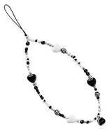 Beaded Strap - A black and white phone charm featuring heart-shaped beads, striped spheres, and small pearls on a black cord.