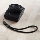 Paracord Lanyard Wrist Strap [2 Pack] - Black woven paracord wrist strap attached to a compact digital camera.