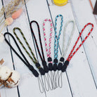 Paracord Lanyard Wrist Strap [2 Pack] - Seven colorful, patterned paracord wrist lanyards with black plastic connectors.