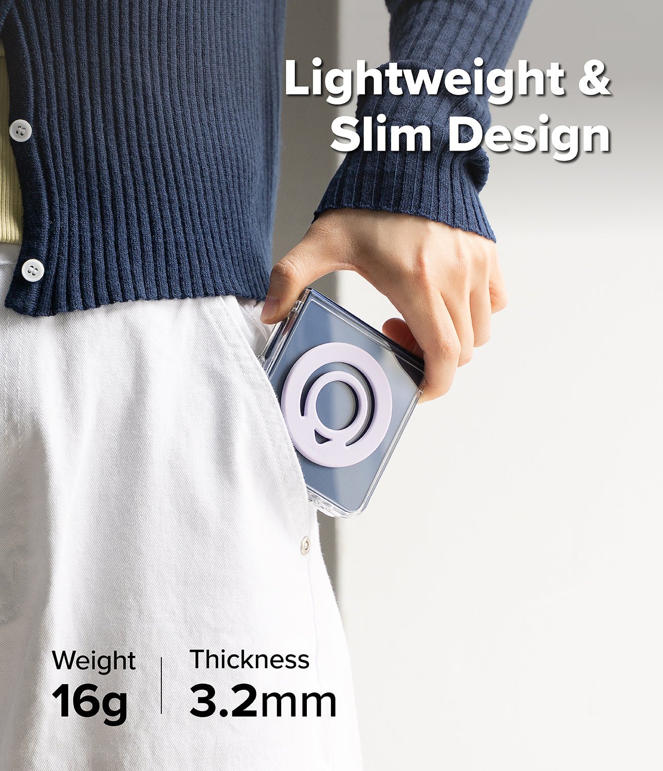 Dual Magnetic Silicone Ring - A person wearing a navy ribbed cardigan and white skirt holds a slim rectangular camera case in their hand. The case is dark gray with a circular white logo.