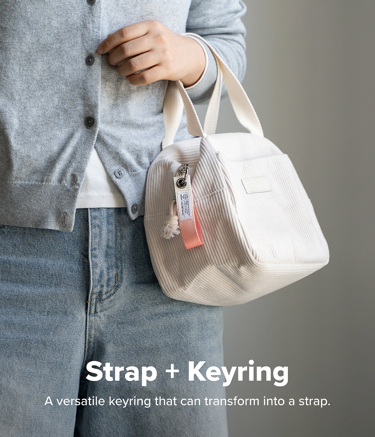Holder Link Eyelet Keyring - A pink and white fabric keyring attached to the zipper of a white corduroy handbag.