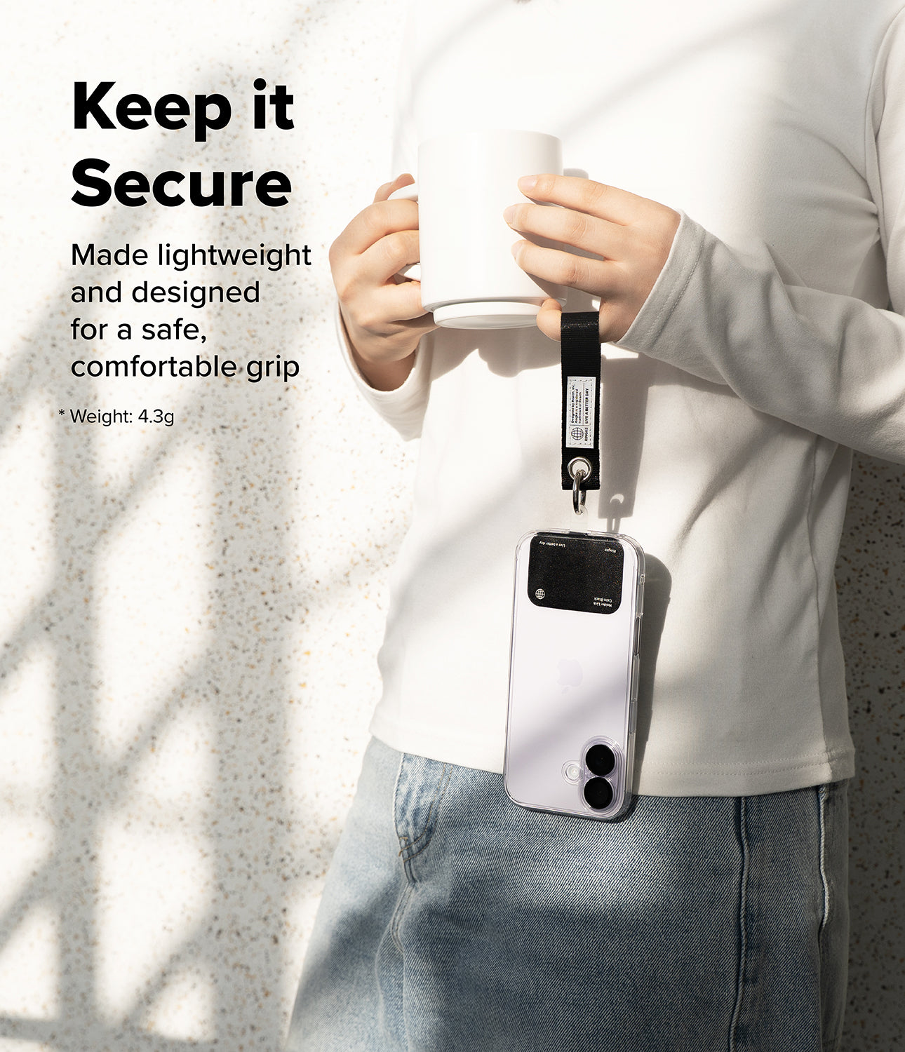 Holder Link Eyelet Keyring - Person holding a mug with a phone attached to their wrist via a black fabric strap and metal ring.