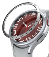 Galaxy Watch 6 Classic 43mm | Bezel Styling - Galaxy Watch 6 Classic 43mm - A silver metal bezel ring hovering above a smartwatch with a red face and white numbers.