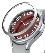 Galaxy Watch 6 Classic 43mm | Bezel Styling - Galaxy Watch 6 Classic 43mm - A silver metal bezel ring hovering above a smartwatch with a red dial and white numerals.