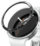 Galaxy Watch 9 / 8 44mm | Bezel Styling - A close-up of a smartwatch with a white band and silver case, showing a black watch dial and a transparent protective bezel ring with white and black numerals.
