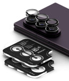 Galaxy Z Fold 8 Ultra | Camera Lens Frame Glass (2 Pack) - Three black phone camera lens protectors with silver edges are shown, with one set applied to the camera lenses of a dark purple smartphone. The other two protectors are stacked in front, displaying printed instructions and the text 'LIKE A BETTER RINGKE'.