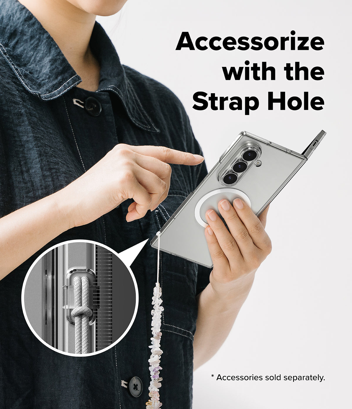 Galaxy Z Fold 8 Ultra Case | Slim Magnetic - A person in a dark denim jacket holds a silver smartphone showing a strap accessory attached through a designated strap hole. The image includes a circular inset close-up of the cord and metal hardware, plus the text 'Accessorize with the Strap Hole' and a note that accessories are sold separately.