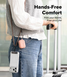 Holder Link Strap | Black - Person wearing a cross-body strap holding a phone case and pink earbud case while pulling luggage.