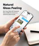 iPhone 18 Pro Max Screen Protector | Easy Slide AR Tempered Glass - A person holds a slim smartphone with a transparent glass back, showing a messaging screen, over a light gray surface with a notebook and pen nearby. Text on the image reads 'Natural Glass Feeling' and describes the easy slide AR tempered glass.