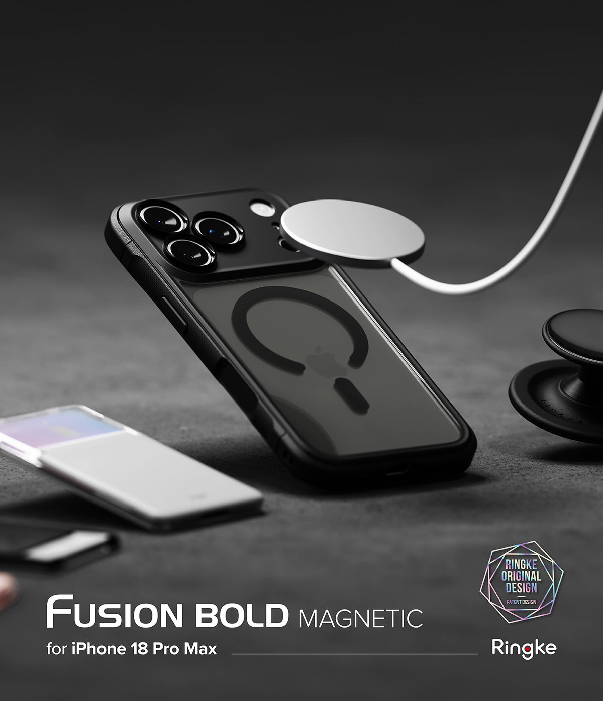 iPhone 18 Pro Max Case | Fusion Bold Magnetic Matte - A black Fusion Bold Magnetic phone case shown on an iPhone, with a white MagSafe ring attached to the back. The image is set on a dark gray textured surface with a blurred white smartphone in the foreground and a pop socket on the right.