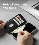iPhone 18 Pro MagSafe Wallet | Folio Grip Wallet Magnetic - A black leather wallet phone case shown open with hands inserting cash and holding cards, placed over a smartphone on a gray surface. White text at the top reads 'Holds Everything You Need' and 'Store up to 4 cards, cash, receipts and more.
