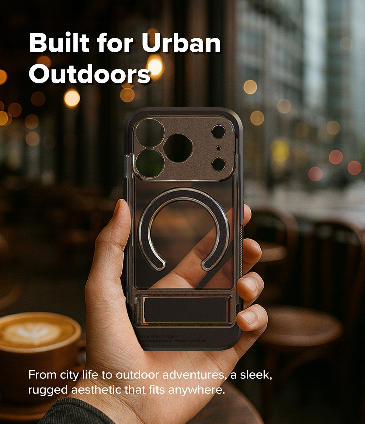 iPhone 18 Pro Case | UX Magnetic - A hand holds a transparent dark gray phone case with a built-in circular ring holder in a blurred urban cafe setting. Text on the image reads 'Built for Urban Outdoors' and 'From city life to outdoor adventures, a sleek, rugged aesthetic that fits anywhere.