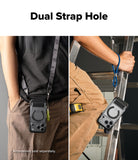 iPhone 18 Pro Case | UX Magnetic - A split-panel demonstration showing a black phone accessory with a circular ring and camera cutouts hanging from a dual-strap system. The left panel shows the strap worn over a person's torso, and the right panel shows the accessory clipped onto a ladder while a person's hand grips the rung.