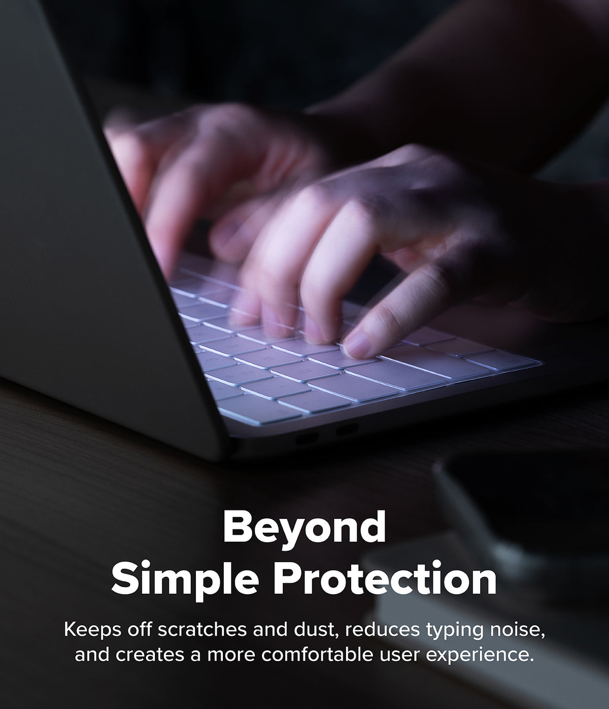 MacBook Neo | Keyskin - A close-up of hands typing on a laptop keyboard in a dim environment, with overlaid text reading 'Beyond Simple Protection' and a descriptive marketing phrase about scratch resistance and typing comfort.