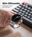 Galaxy Watch 9 / 8 | Metal One Air - A hand holds a slim round smartwatch with a silver metal link band and a black display, with a blurred keyboard and desk surface in the background. Text at the top reads 'Slim Silhouette' and 'Featherlight comfort for all-day wear.