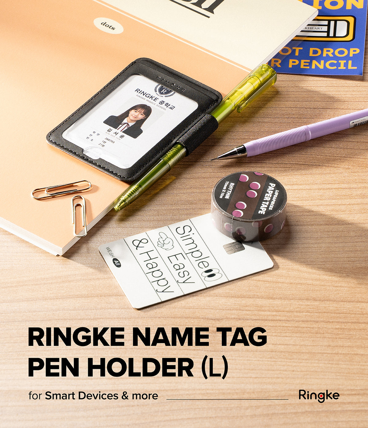 Pen Holder | Name Tag (2P) - A Ringke name tag pen holder in black faux leather, shown holding a sample ID badge. The holder is styled on a wooden desk with a green pen, a purple mechanical pencil, a gold paperclip, and a roll of washi tape.