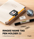 Pen Holder | Name Tag (2P) - A Ringke name tag pen holder set displayed on a light wood desk, featuring a black ring holder with a sample photo, a yellow pencil, a black marker, paper clips, washi tape, and a small card. Text at the bottom reads 'RINGKE NAME TAG PEN HOLDER (S)'.
