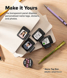 Pen Holder | Name Tag (2P) - Personalized name tags displayed on a stack of beige envelopes on a wooden desk, with text reading 'Make it Yours' and product details. The name tags are shown in black frames with sample photos and labels, alongside pens and stationery props.