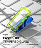 Google Pixel 10a Screen Protector | Easy Slide Tempered Glass - Ringke Easy Slide Tempered Glass screen protector shown in a translucent neon green protective sleeve, sliding off a blue Google Pixel 10a smartphone placed on a white keyboard.