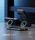 Google Pixel 11 Pro XL Case | Onyx Ring - Three black phone cases with circular Ring kickstands are displayed on a dark tabletop against a blue perforated panel background. One case is propped upright, one is tilted, and one lies flat.
