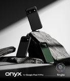Pixel 11 Pro Case | Onyx - Three phone cases displayed on dark rocks in a styled studio setup. Two cases are matte black and one is dark green.