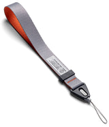 Design Hand Strap - Gray and orange fabric wrist strap with a black plastic connector and a thin loop for device attachment.