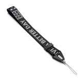 Hand Strap | Lettering - Black fabric wrist strap with white "BETTER DAY" text, black plastic buckle, and thin gray loop.