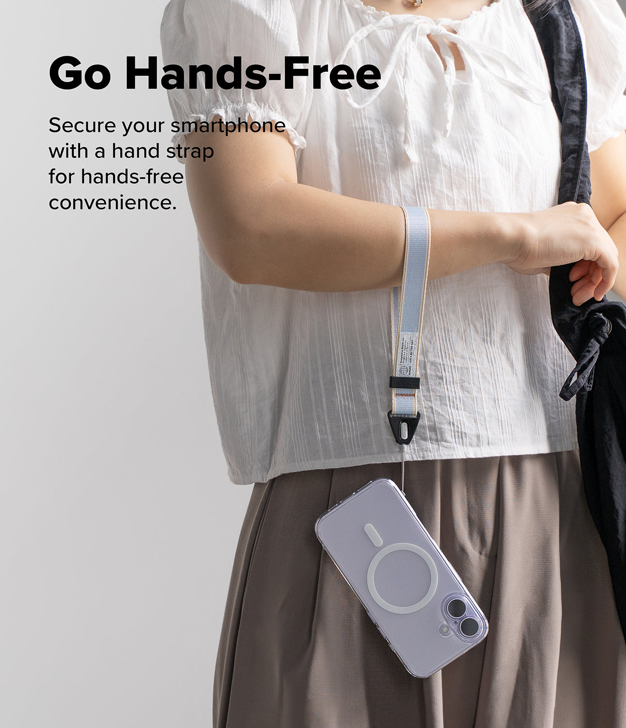 Person holding a phone with a hand strap on a plain background