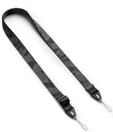 Design Shoulder Strap - Person wearing a phone on a camo shoulder strap while holding a shopping bag and opening a door.